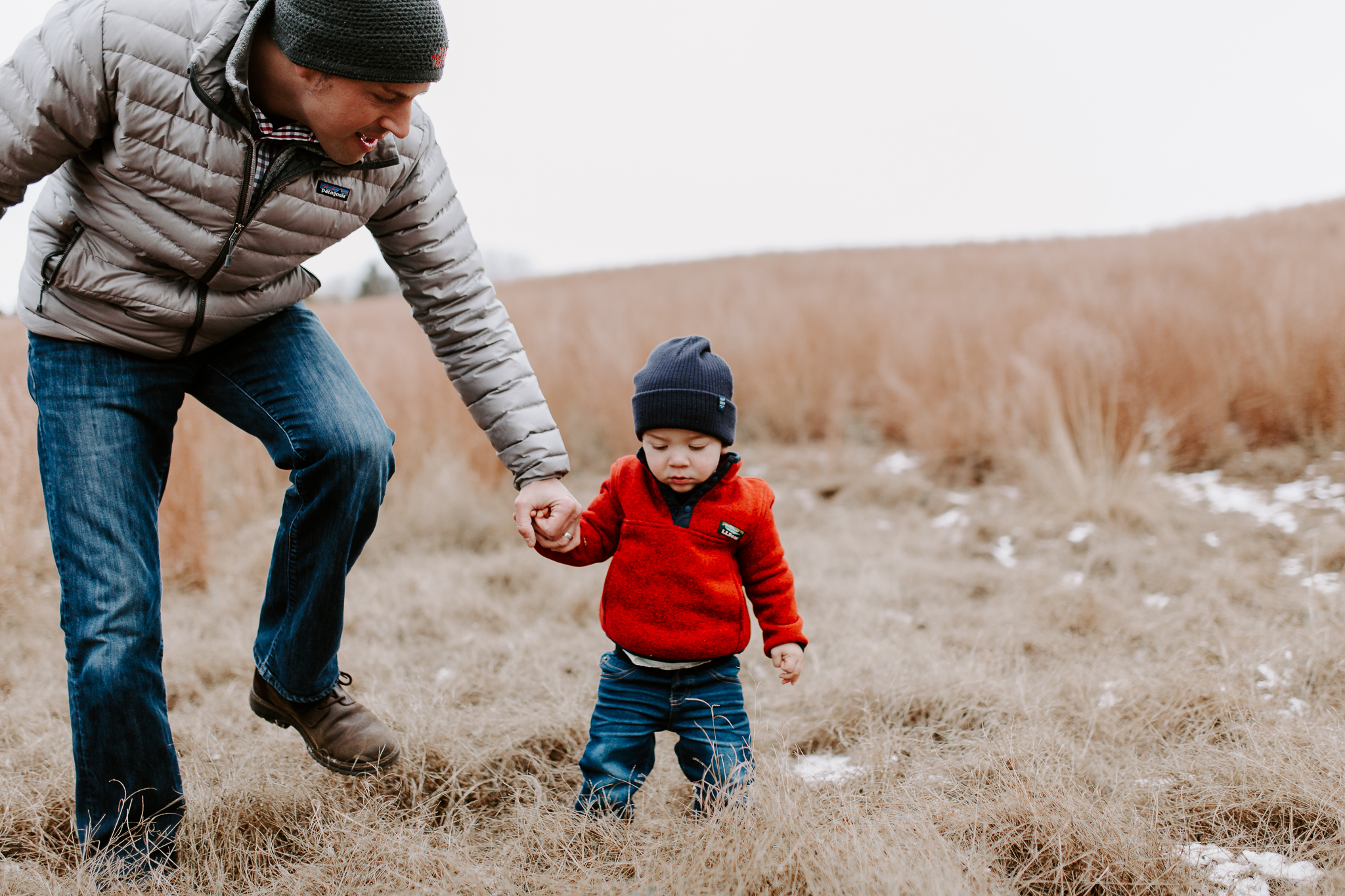 Father holding his toddler boy's hand outside.